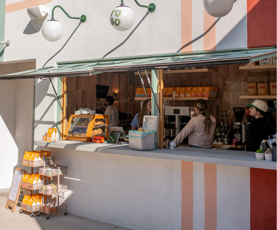 Modern outdoor cafe in New Buffalo, Michigan with striped wall and people working inside a coffee service window serving Infusco Coffee. 